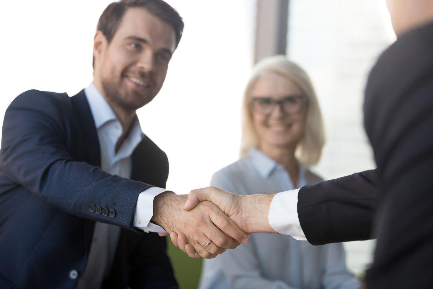 Smiling successful businessmen in suits shaking hands